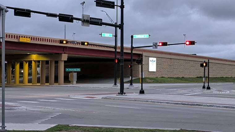 The signalized intersection of California Street and the I-35 frontage road beneath the overpass at dusk.
